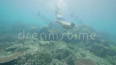 年轻人在美丽的海洋里浮潜，在水下看热带鱼和珊瑚礁。